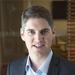 Professional headshot of Jordan Krawll wearing a navy blazer and light blue shirt