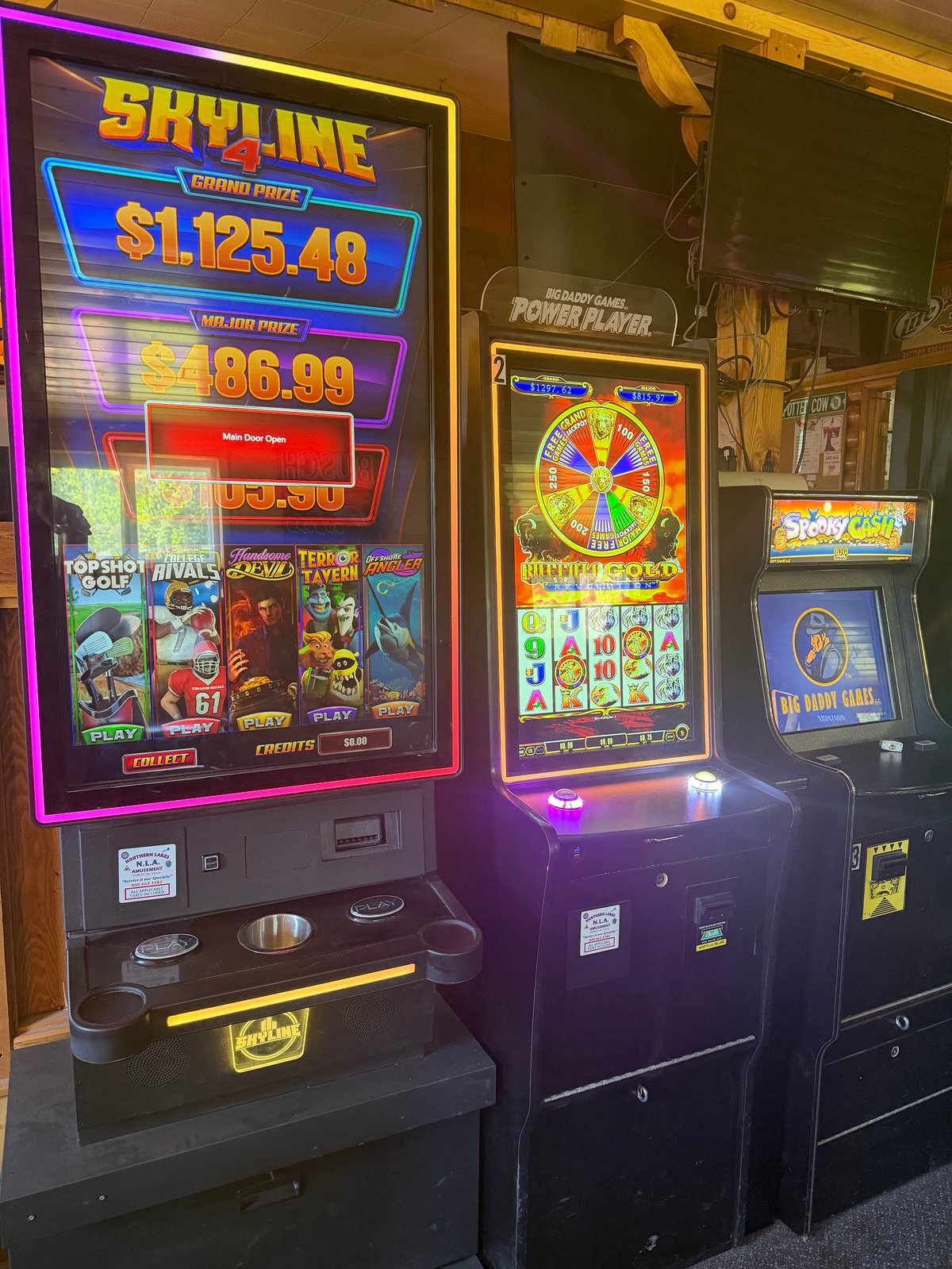 Row of illuminated slot machines in a casino, including a purple-framed Skyline machine displaying game amounts and a yellow-framed wheel game.