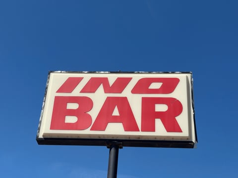 Red and white NO BAR vintage neon-style sign mounted on a pole against a blue sky