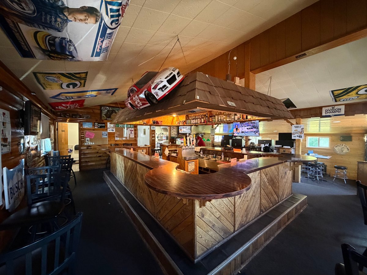 Interior of a vintage car-themed diner with wooden counter, memorabilia on walls and ceiling, and classic automotive decorations