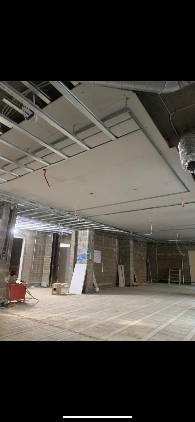 MF ceiling grid framework with ducting above, boards being fixed, commercial project.