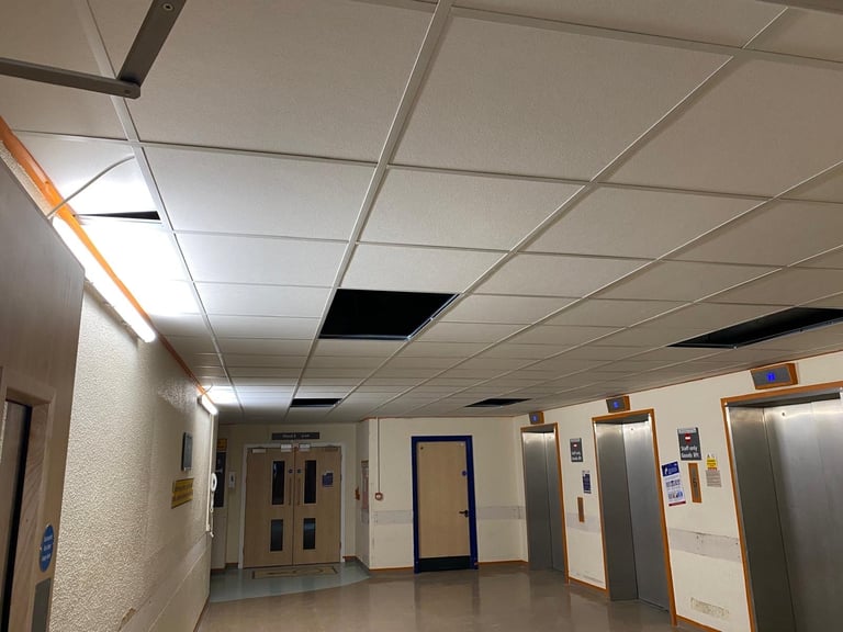Completed lay-in grid suspended ceiling in a hospital corridor near the lift lobby.