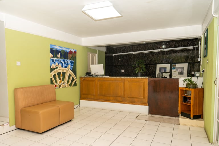Modern hotel lobby with yellow walls, orange leather seating, wooden reception desk at BayPort Residence Inn