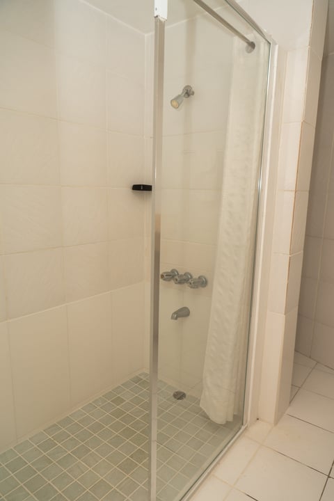 Modern glass shower enclosure with metal framing, clear glass doors, and tiled walls in a white bathroom