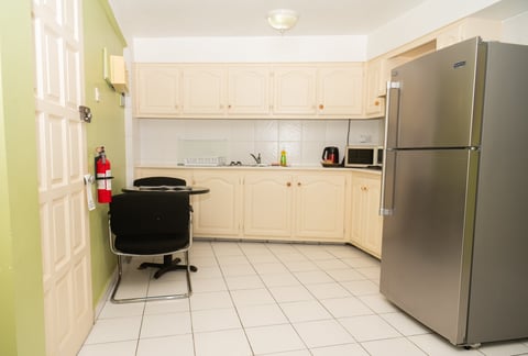 Modern kitchen with cream cabinets, stainless steel refrigerator, and white tile flooring