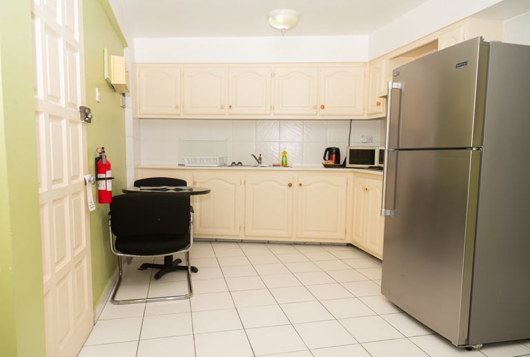 Modern kitchen with cream cabinets, stainless steel refrigerator, and green accent wall