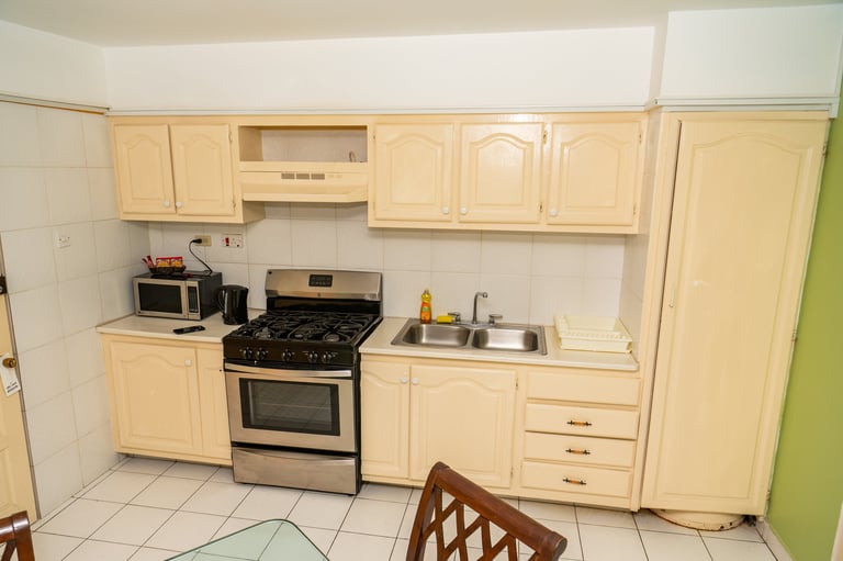 Compact kitchen with cream-colored cabinets and stainless steel gas range