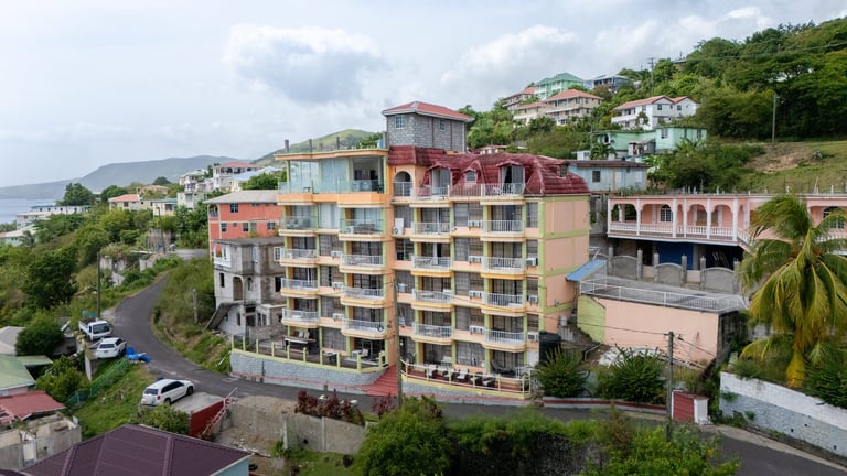 Colorful residential buildings on a hillside tropical island with lush vegetation and ocean view