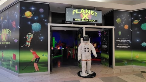 Entrance to Planet X Mini Glow Golf with astronaut statue and glowing planet displays