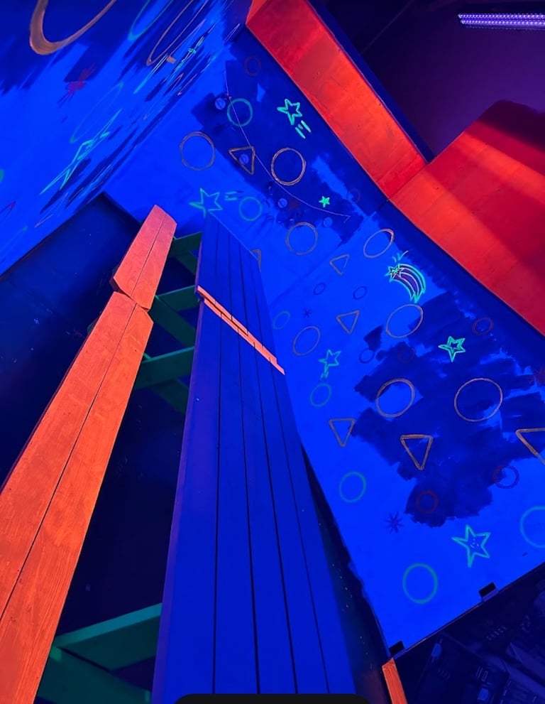 Neon-lit modern building facade with bright blue and red LED lights, geometric shapes, and cosmic symbols on the display