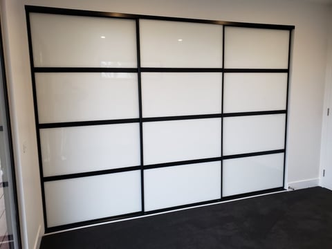 Sliding wardrobe doors with black metal frames and frosted glass panels, fitted by The Wardrobe Guy
