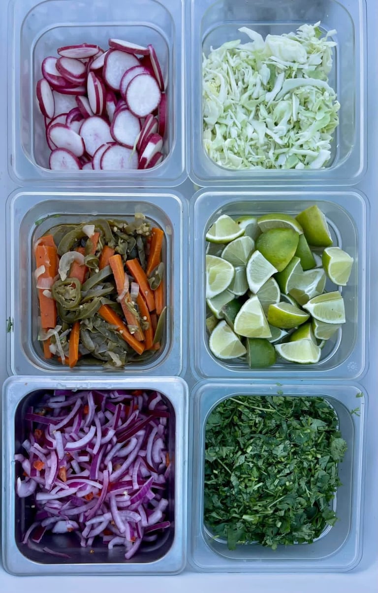 Six clear meal prep containers filled with sliced and chopped vegetables including radishes, shredded cabbage, lime wedges, and leafy greens