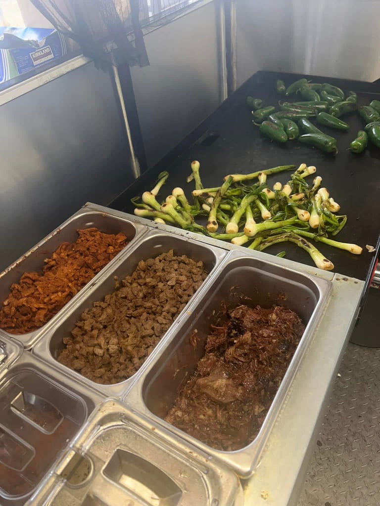 Food service counter with metal pans containing cooked ground meat and sauteed green beans and peppers