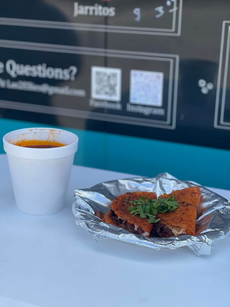 White cup of coffee next to a wrapped burrito with cilantro on a counter, with a menu board in the background
