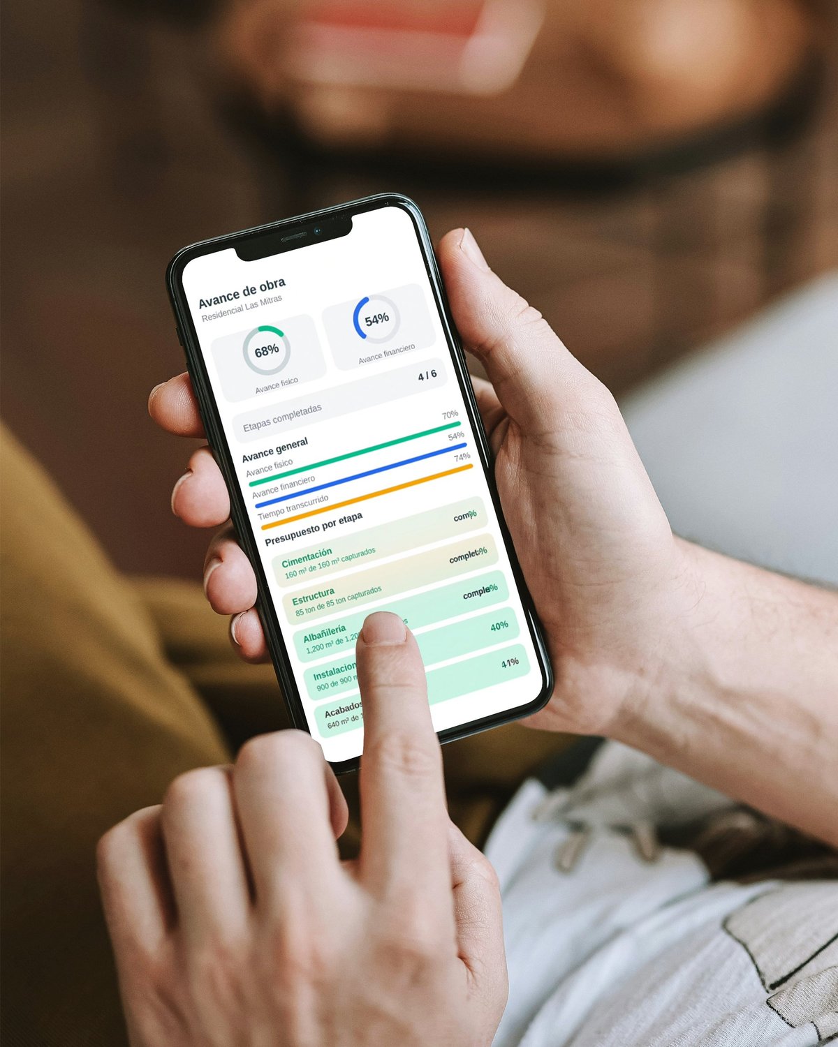 Persona revisando en su teléfono la app de seguimiento de obra con avance físico, financiero y etapas del proyecto