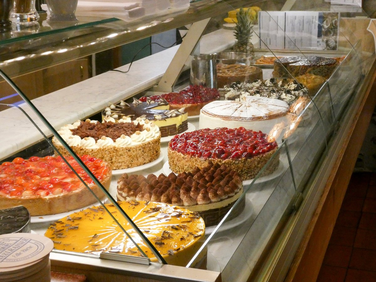 Vitrine mit verschiedenen verzierten Torten und Törtchen, belegt mit frischen Beeren, Sahne und Garnituren