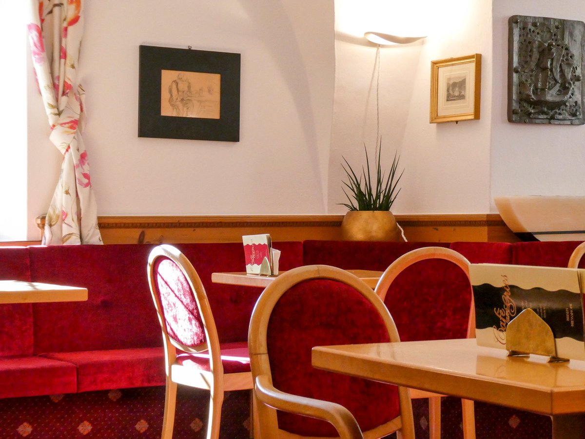 Gemütliche rote Sitzbänke und Holztische im Innenraum des Café am Gries