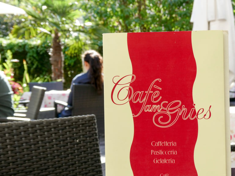 Speisekarten-Aufsteller des Café am Gries in Rot und Creme im Garten vor der Terrasse