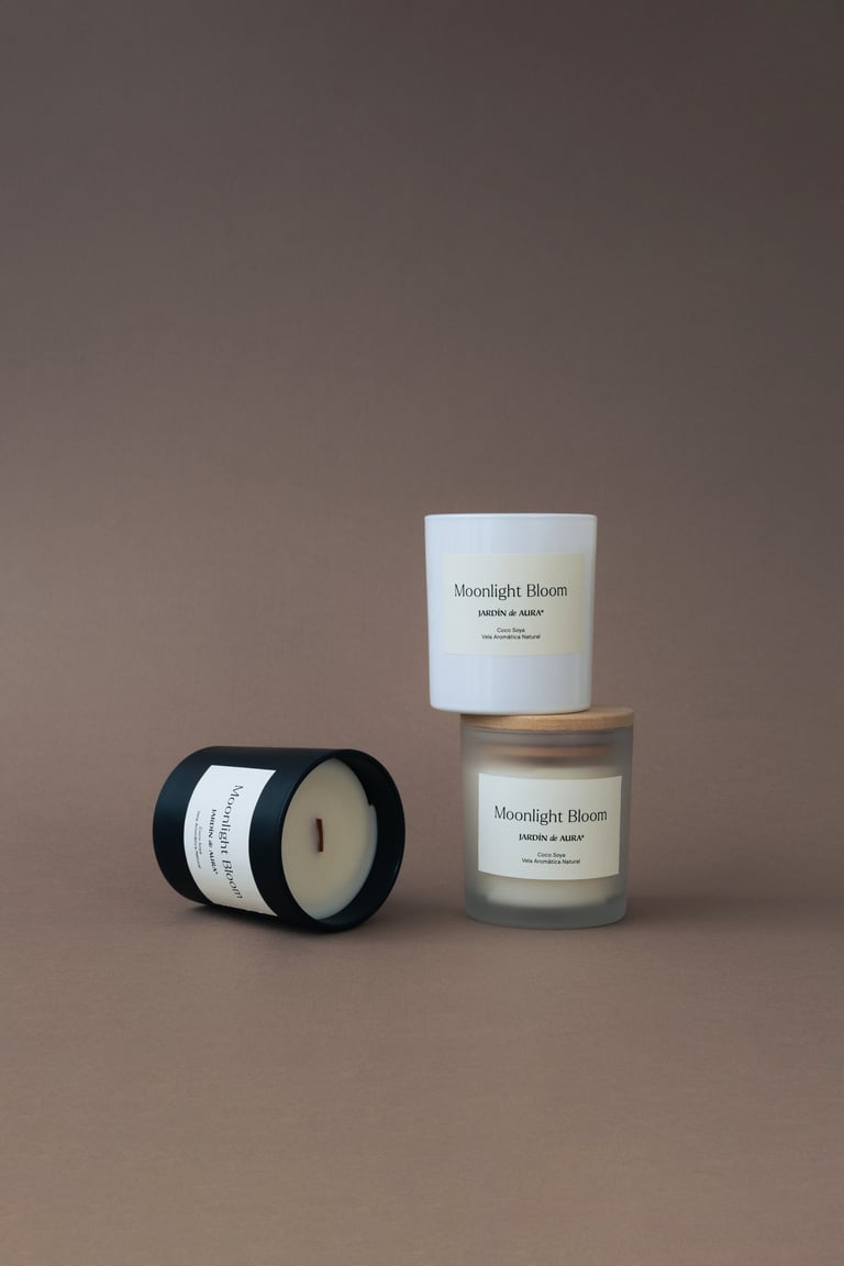 Three Moonlight Bloom scented candles in white and black containers displayed against a neutral beige background