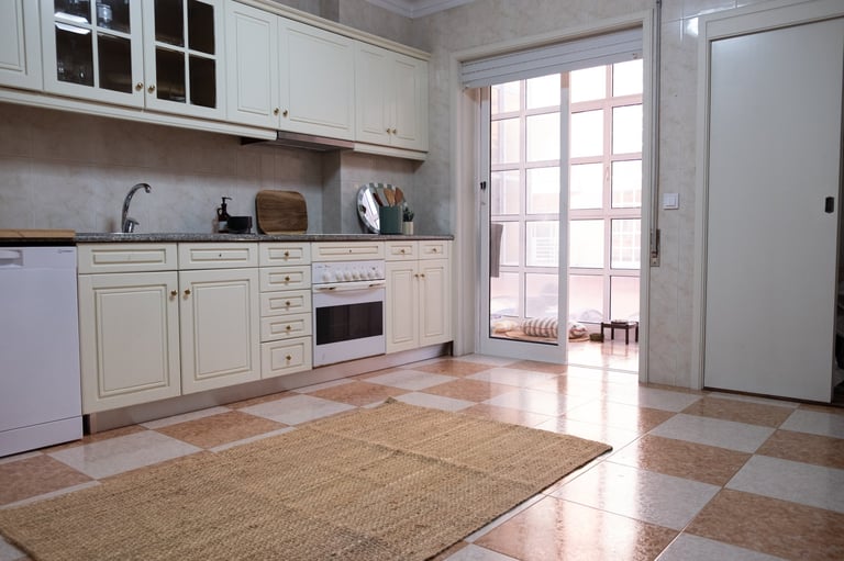 Modern kitchen with white cabinetry, stainless steel appliances, light wood flooring, and French doors opening to a balcony