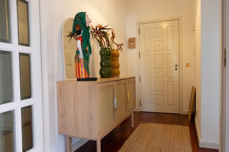 A wooden cabinet in a hallway displays decorative plants and objects, with doors and natural lighting visible in the background