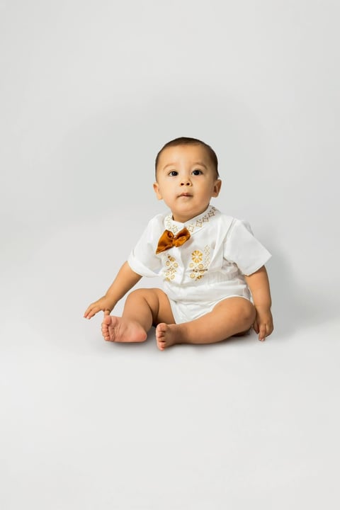 Bebé Andrés vestido de blanco con moño dorado