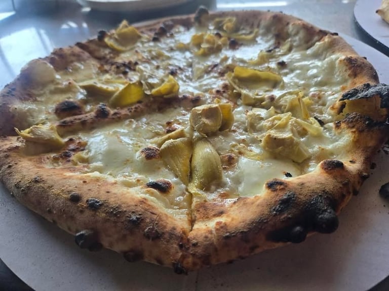 Wood-fired pizza with melted cheese and sliced green peppers on a charred crust
