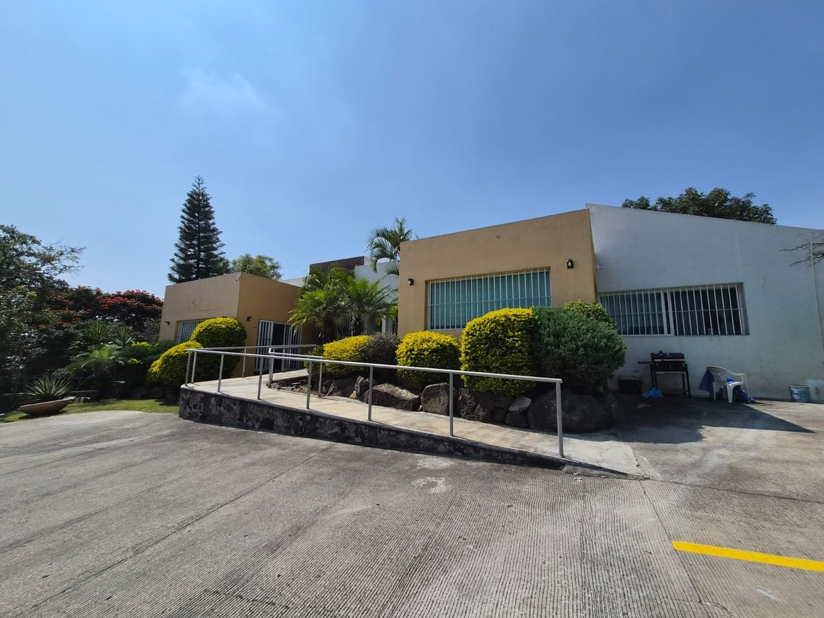 Fachada moderna de la clínica con rampa de acceso y jardinería frente al cielo despejado
