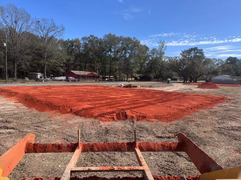 Orange metal horse arena or round pen under construction in a rural paddock with trees and farm buildings in background
