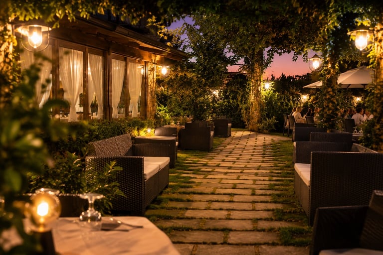 Patio esterno del ristorante al tramonto con verde e luci calde