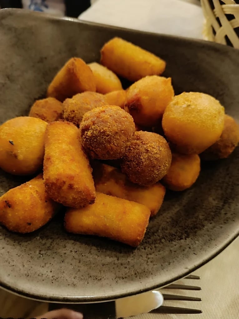 Crocchette dorate e palline di formaggio fritte su piatto di ceramica