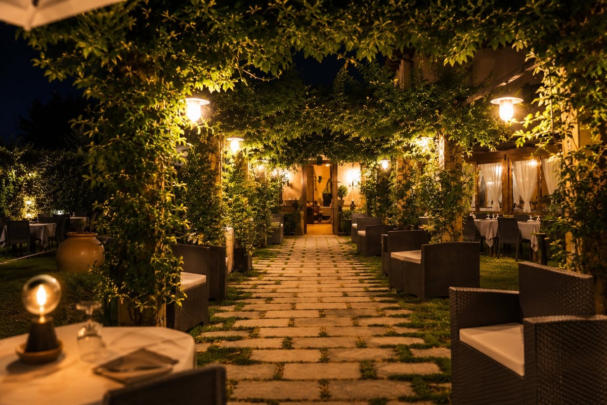Patio esterno illuminato la sera con pareti di edera e luci