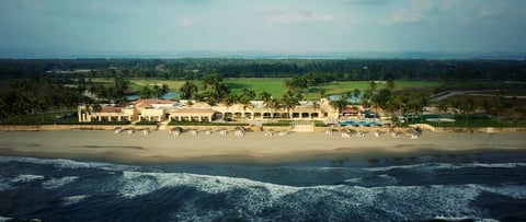Vista aérea de resort frente a la playa con palmeras en Tres Vidas, Acapulco