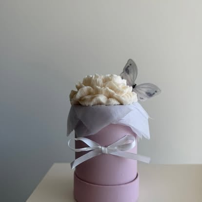 Flowerbox NEORA z kremowymi kwiatami w różowym pudełku z białą wstążką i dekoracją motyla