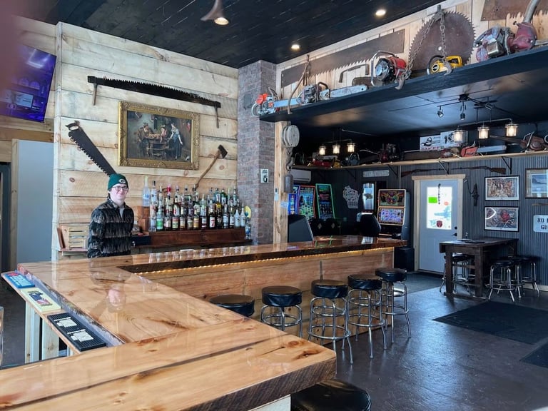 Interior of a rustic bar with wooden countertops, bottles displayed on shelves, and bar seating with industrial decor
