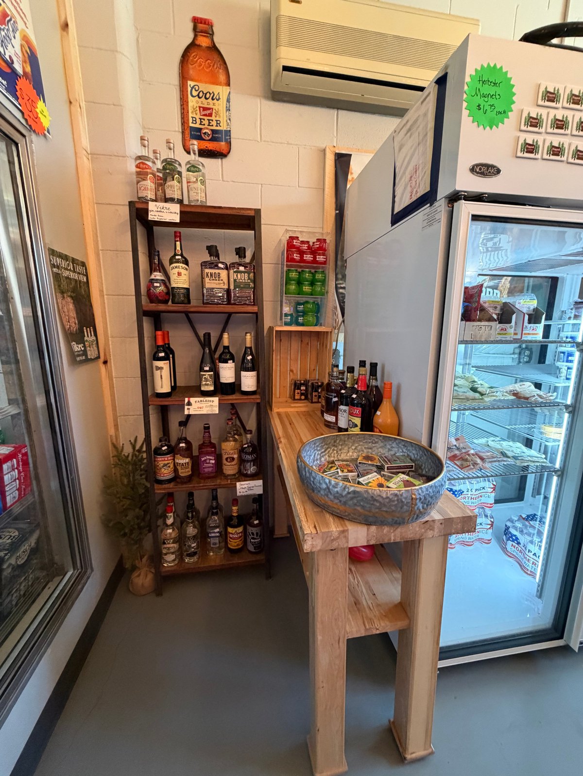 Wooden shelf of liquor bottles, vintage Coors Beer sign, and a large galvanized tub of pull tabs