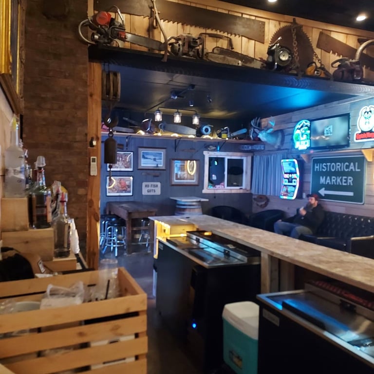 Interior of a vintage-themed bar or diner with blue walls, neon signs, memorabilia, a counter, and arcade games.