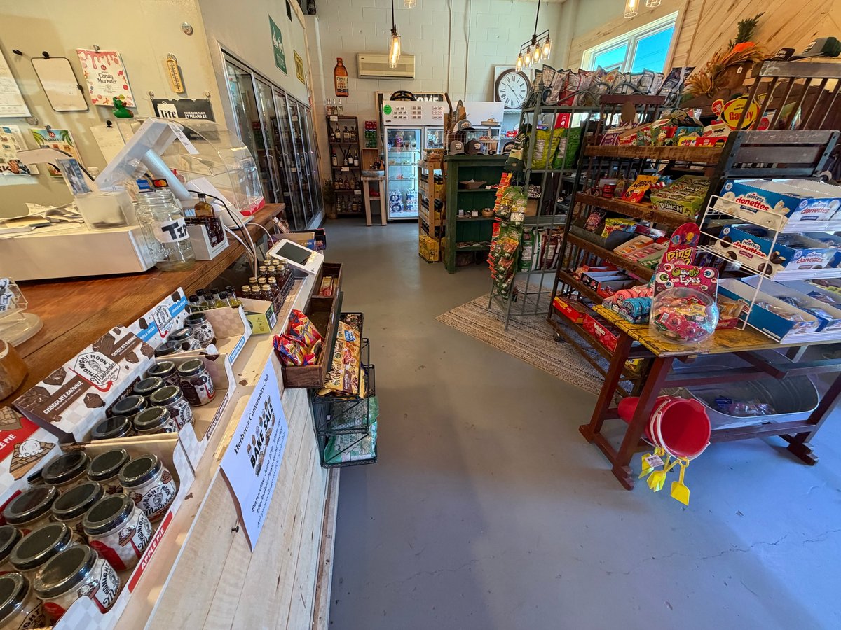 Wide view of the general store interior showing coolers, snack shelves, candy displays, and Hostess Donuts