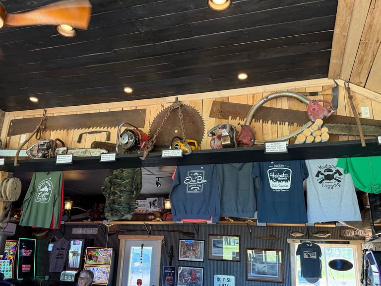 Retail shop display with mounted tools on upper shelves, hanging t-shirts and merchandise in the middle, and products displayed below