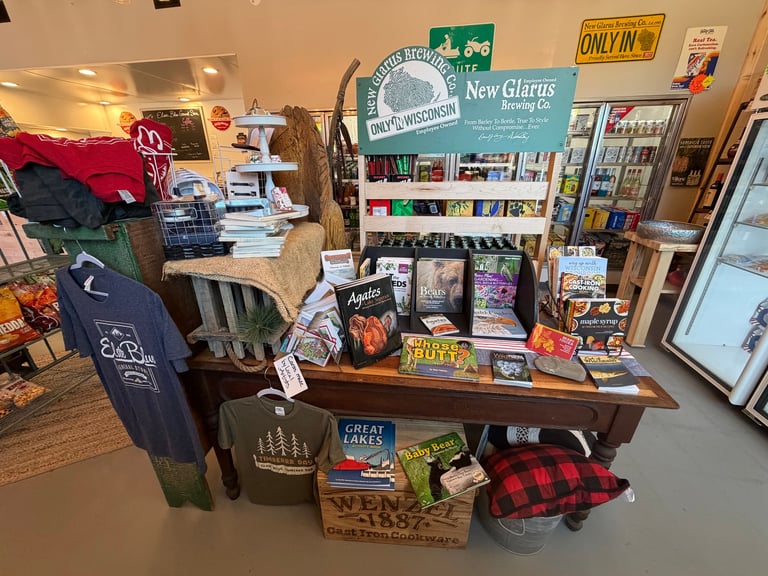 Retail display table in shop with merchandise including clothing, books, and accessories featuring vintage signage and local goods
