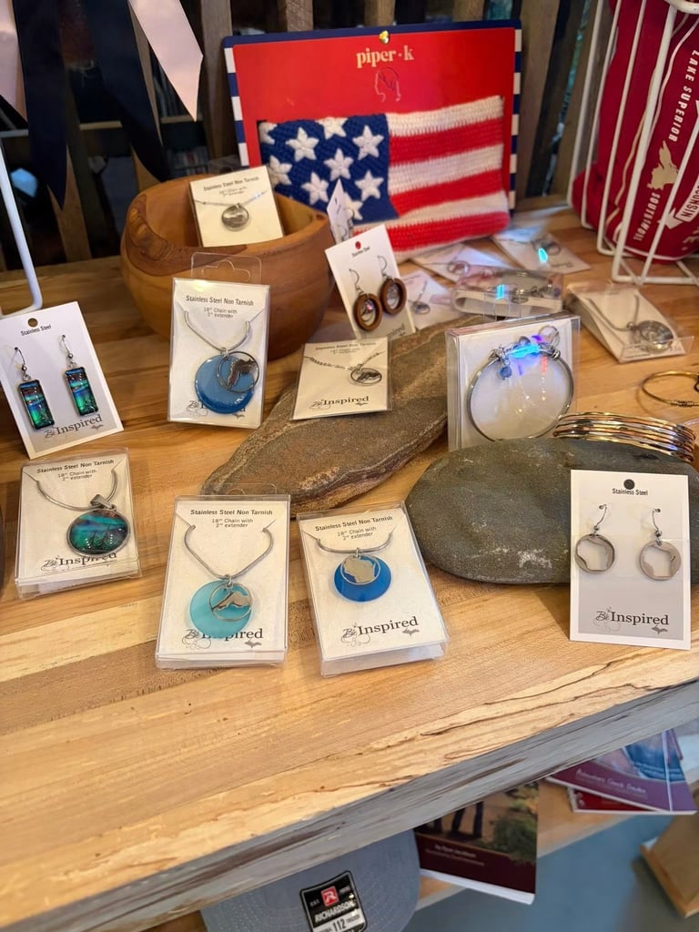 Handmade jewelry and crafts display on wooden table featuring necklaces, earrings, and decorative items with American flag decor in background