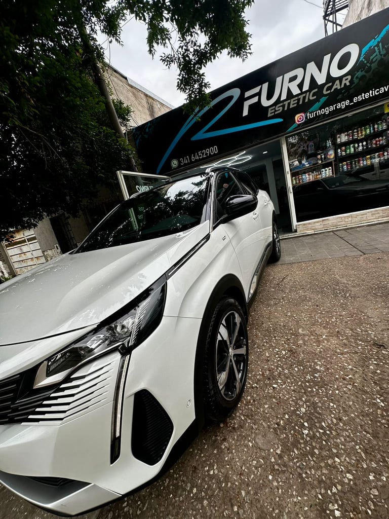 White sedan parked outside Furno auto repair garage with ivy-covered wall and storefront signage visible