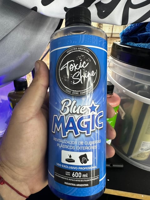 Hand holding a blue bottle of Toxic Shine Blue Magic plastic revitalizer, 600ml, professional use product from Argentina