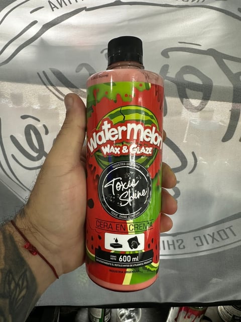 Hand holding a 600ml bottle of Watermelon Wax and Glaze automotive product with red and green label