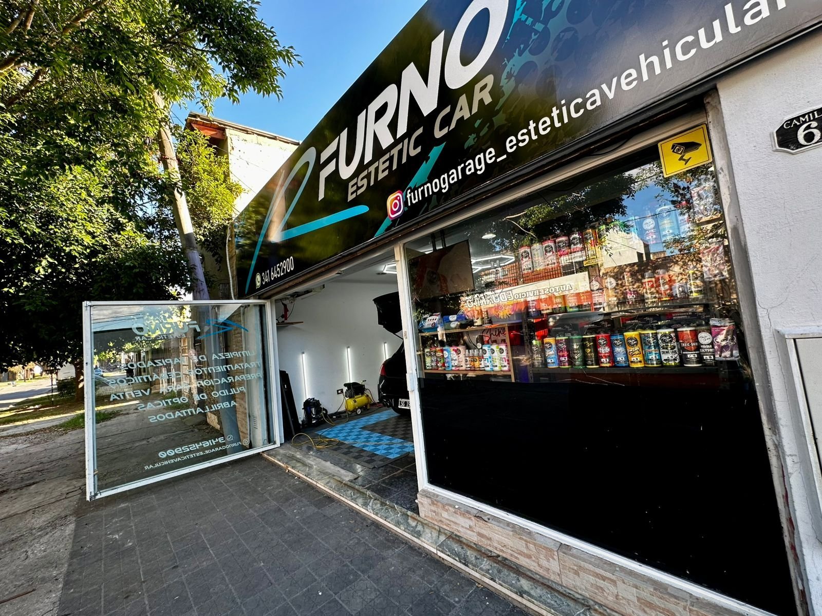 Exterior of Furno Garage car cosmetic shop with dark storefront, signage, and product displays visible through windows on a sunny day