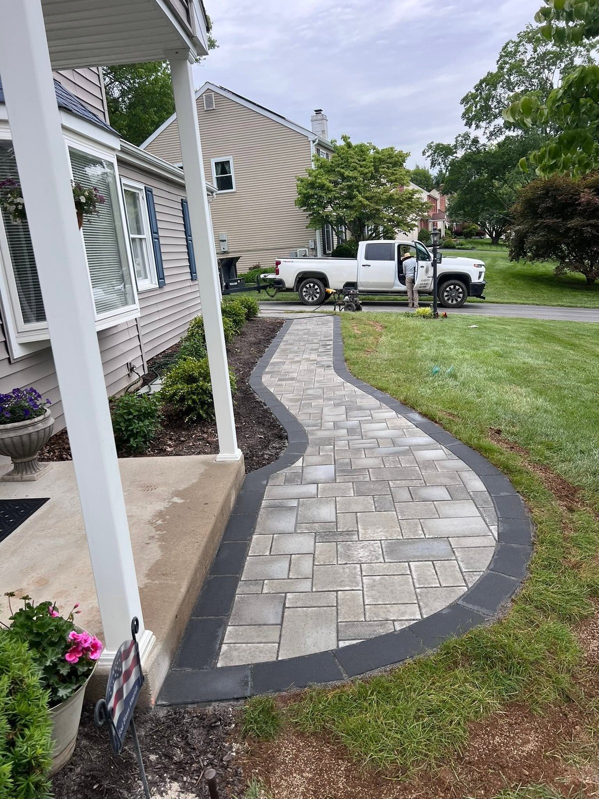 Newly installed curved paver walkway with dark border edging along the home