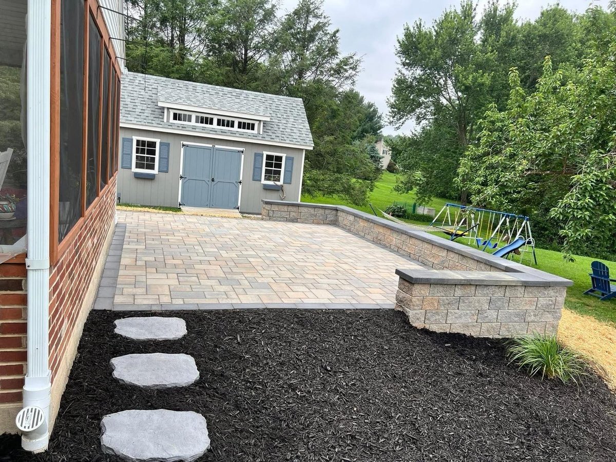 Backyard patio with gray storage shed, paver walkway, stepping stones, and manicured lawn with wooden fence