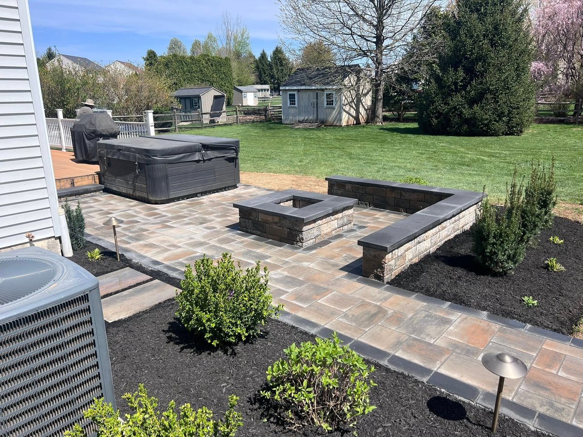 Backyard patio with stone seating area, sunken fire pit, hot tub, and manicured landscaping