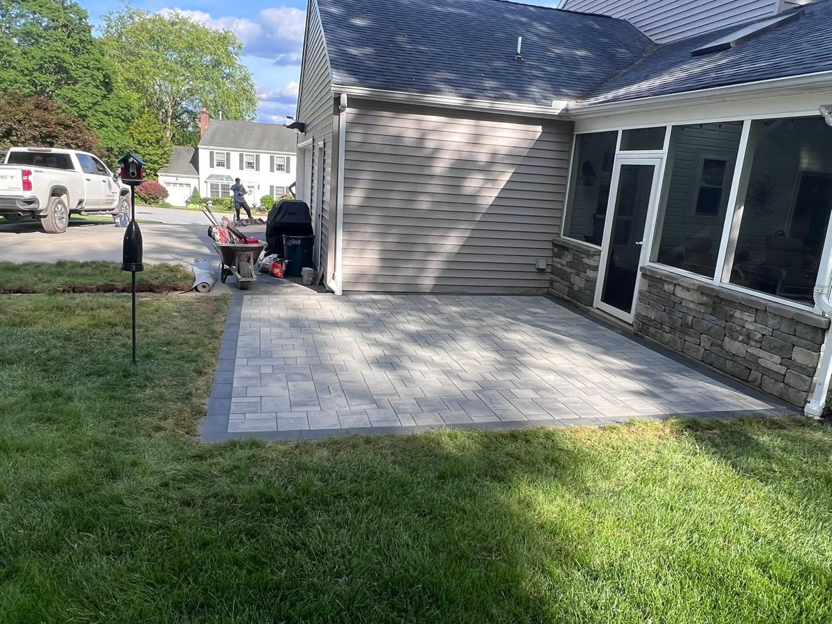 Newly installed gray paver patio with clean lines against home
