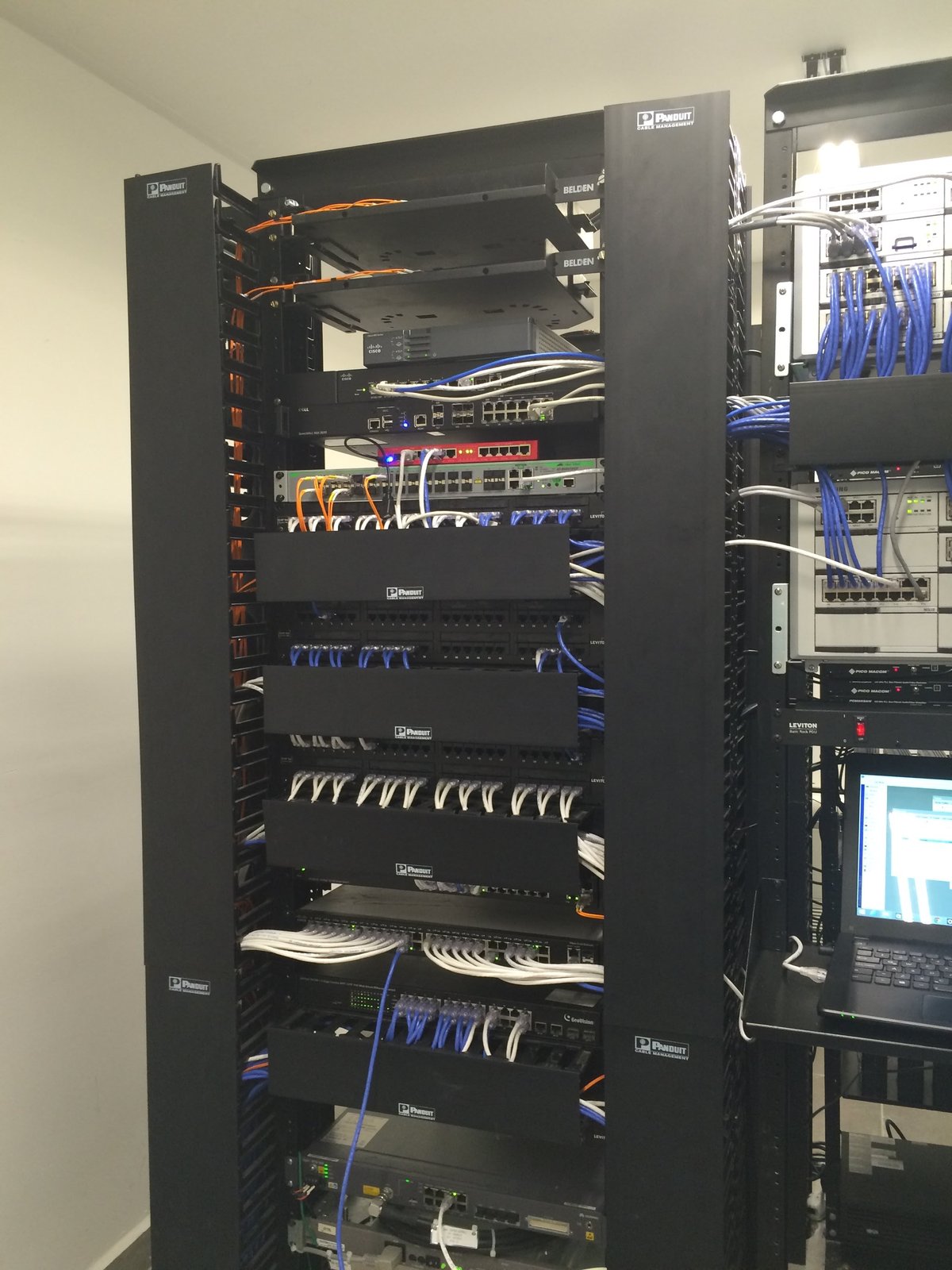 Rack de comunicaciones con switches y patch panels, y cableado estructurado conectado en un cuarto técnico